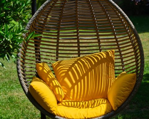 a swing chair with a yellow pillow on it